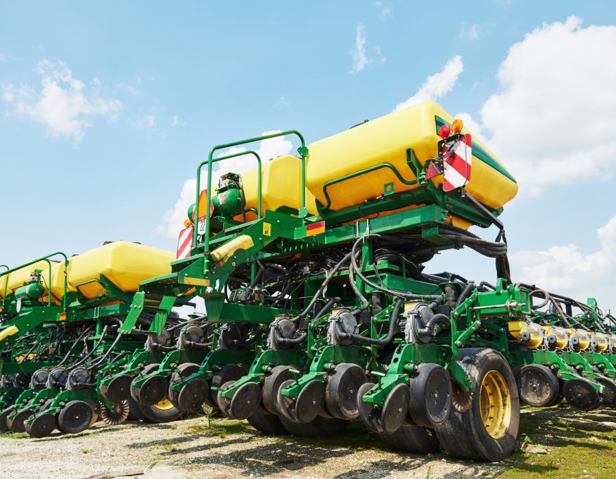 Close up of seeder attached to tractor in field. Agricultural machinery for spring works sowing, seeding